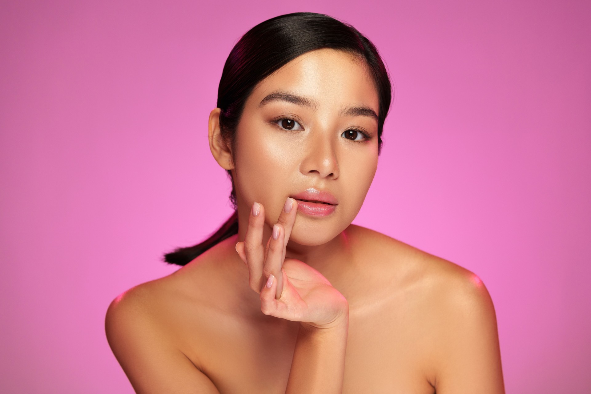 Beautiful model poses gracefully with soft lighting on pink background