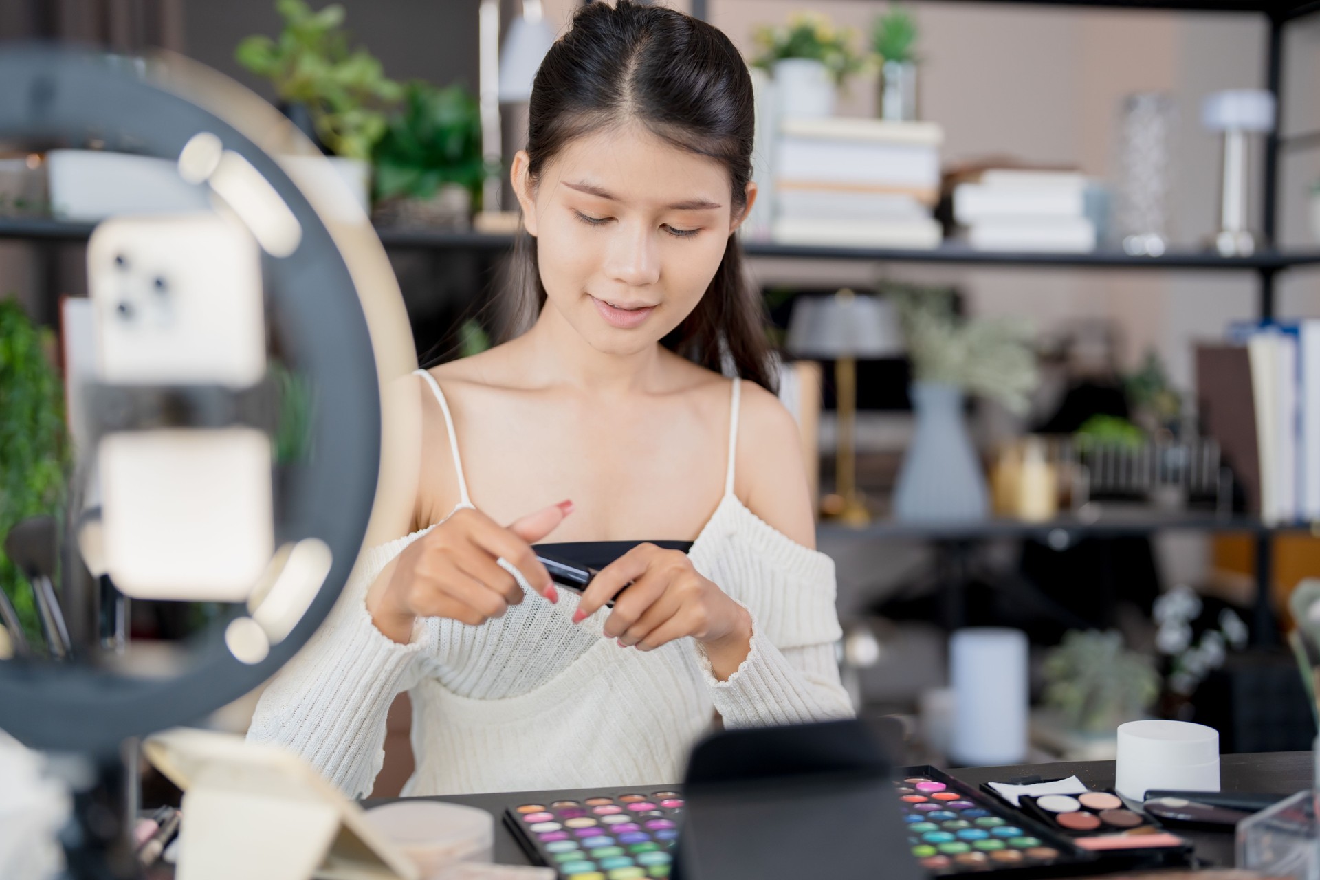 Asia woman beauty influencer makeup artist vlogger live streaming makeup tutorial on smartphone for social media